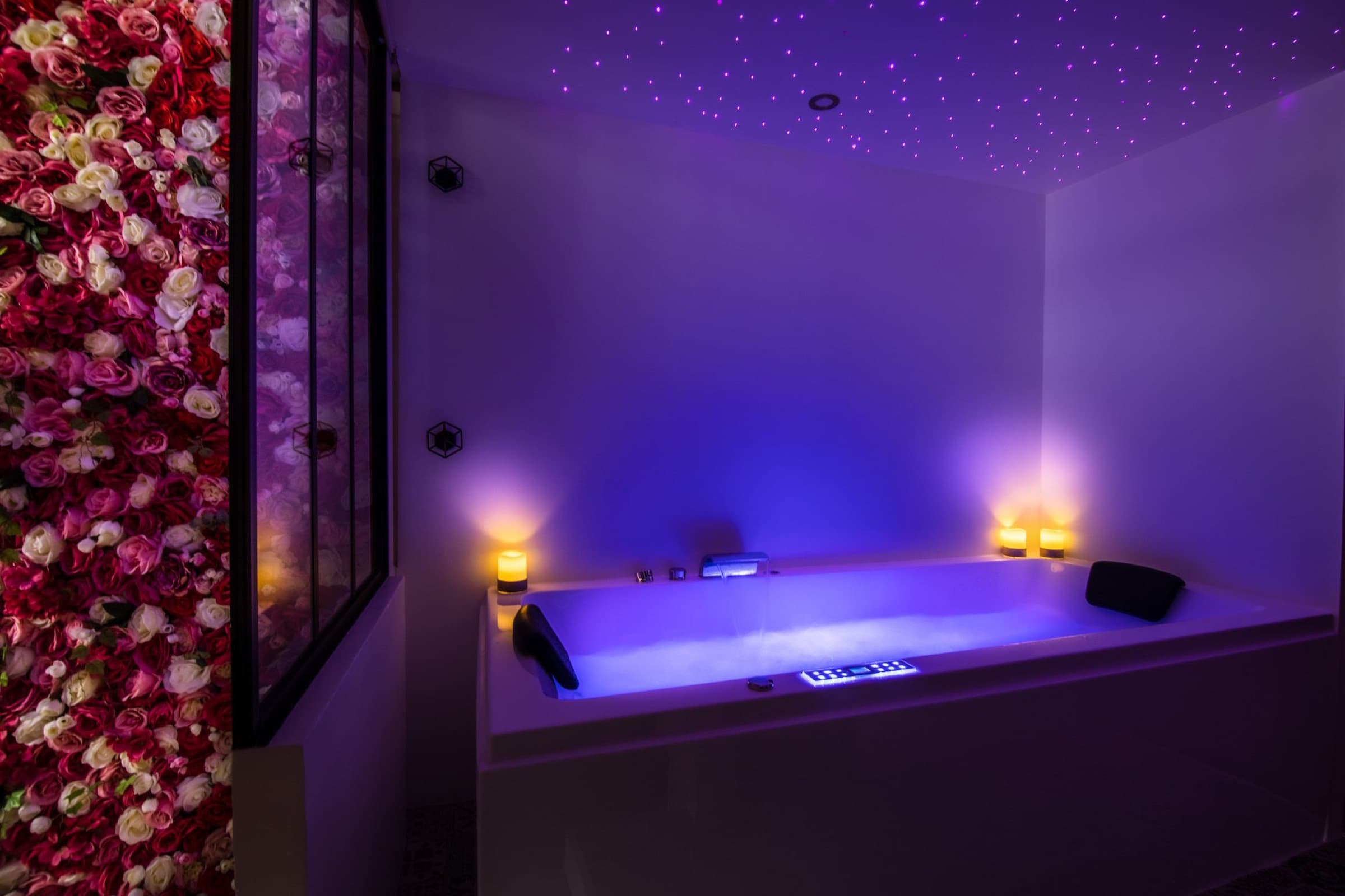 Jacuzzi glowing blue beneath the starry ceiling, lit candles and wall of roses.