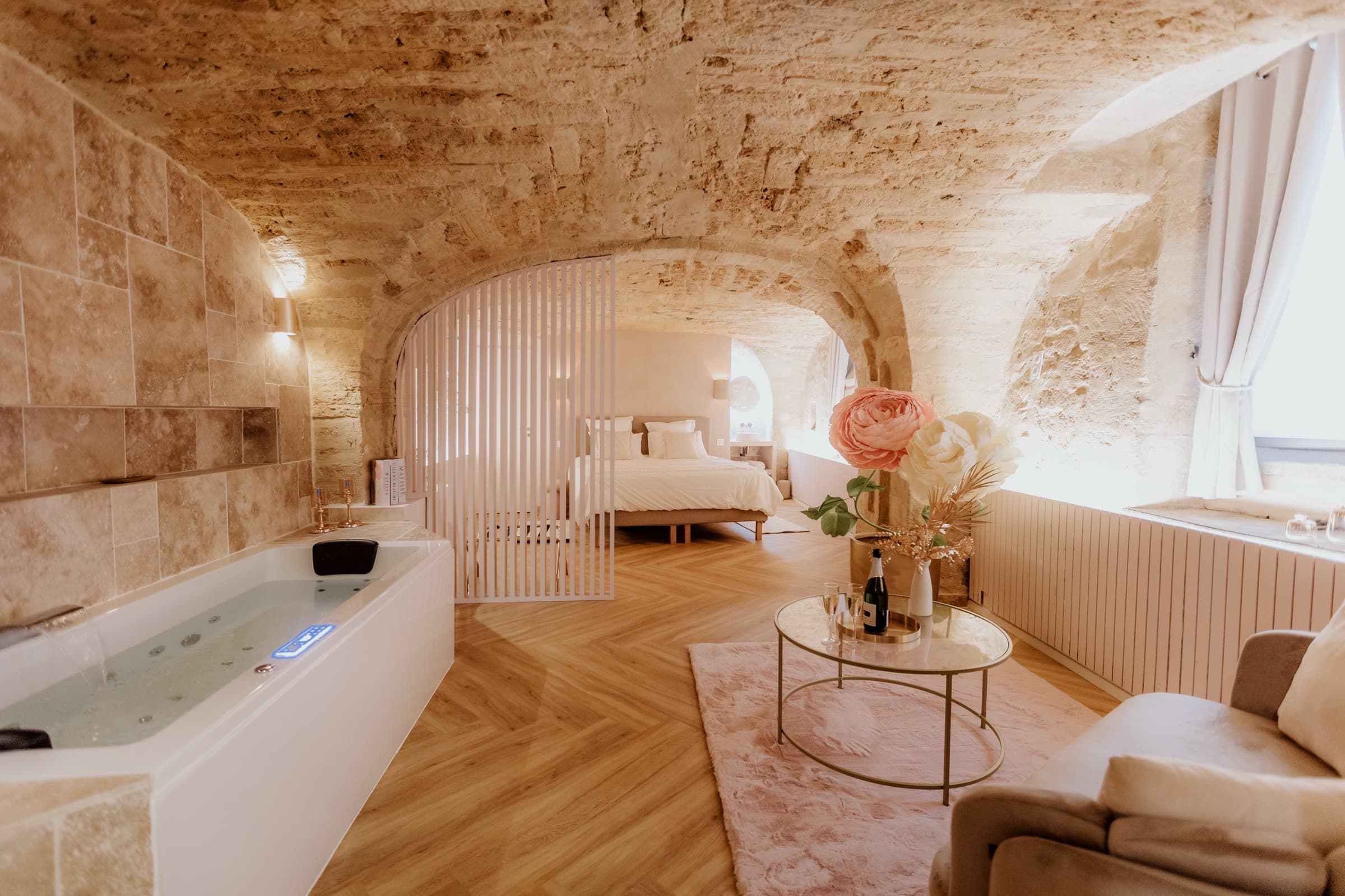 Filled jacuzzi, seating corner and bed arranged beneath the stone vault